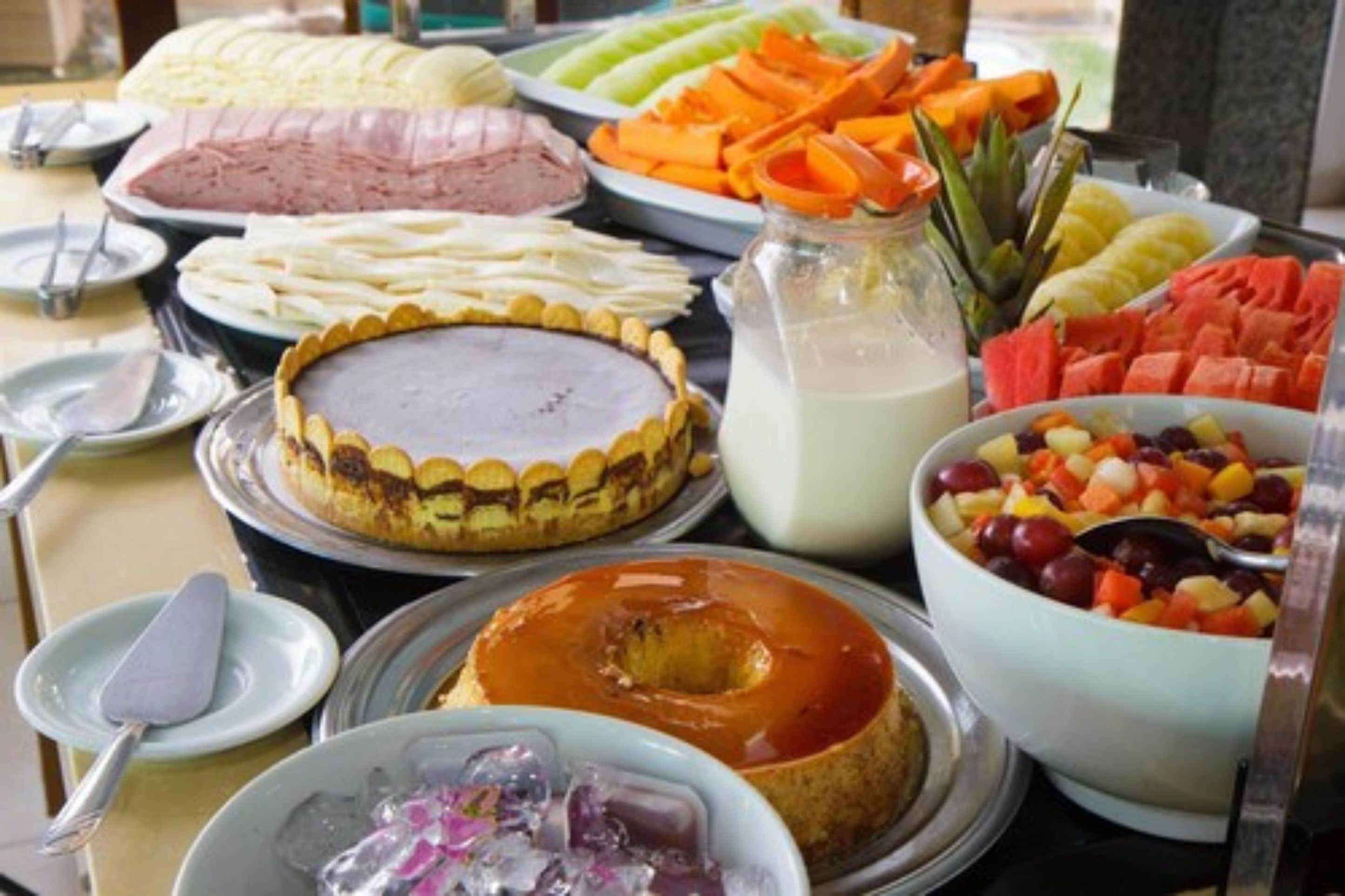 A buffet with various dishes including a cake, fruit, and a bowl of mixed vegetables.