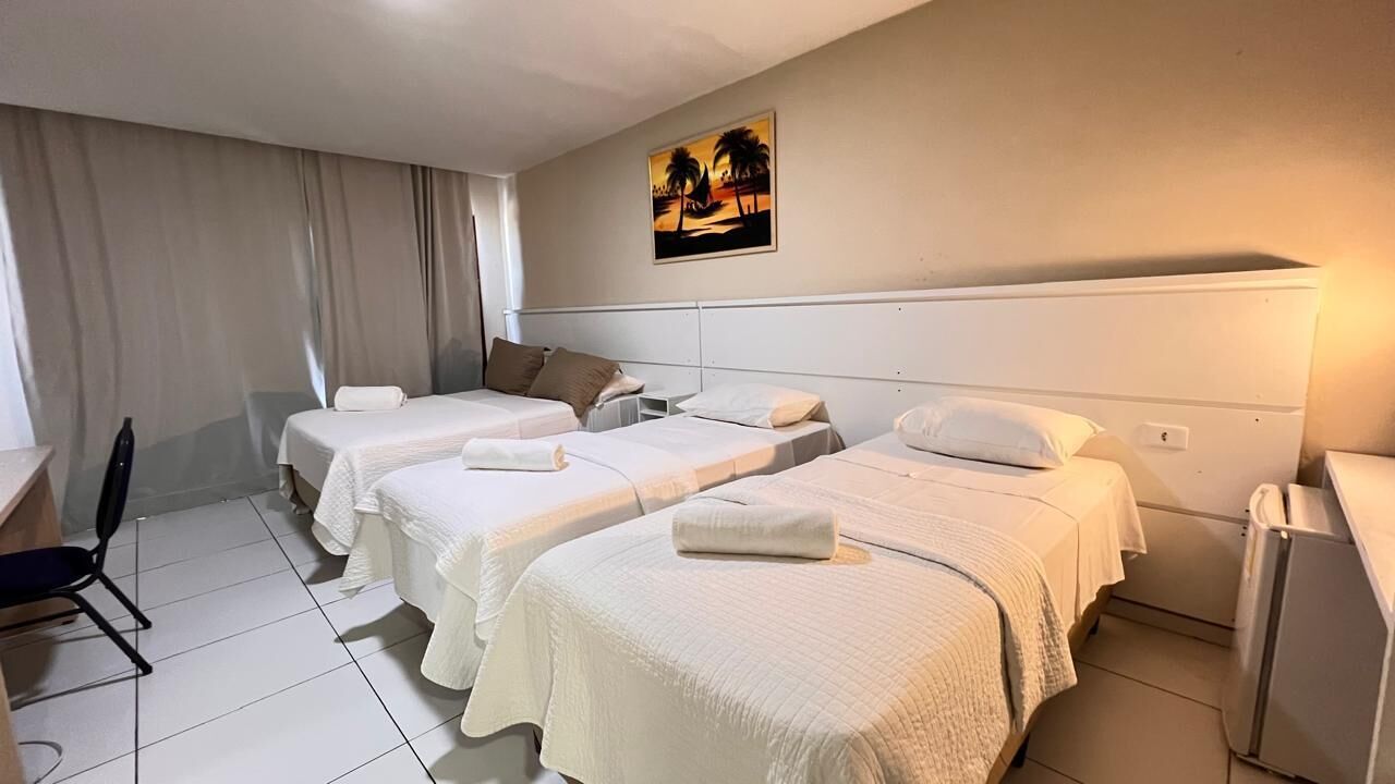 A hotel room with three beds, a desk, and a chair.