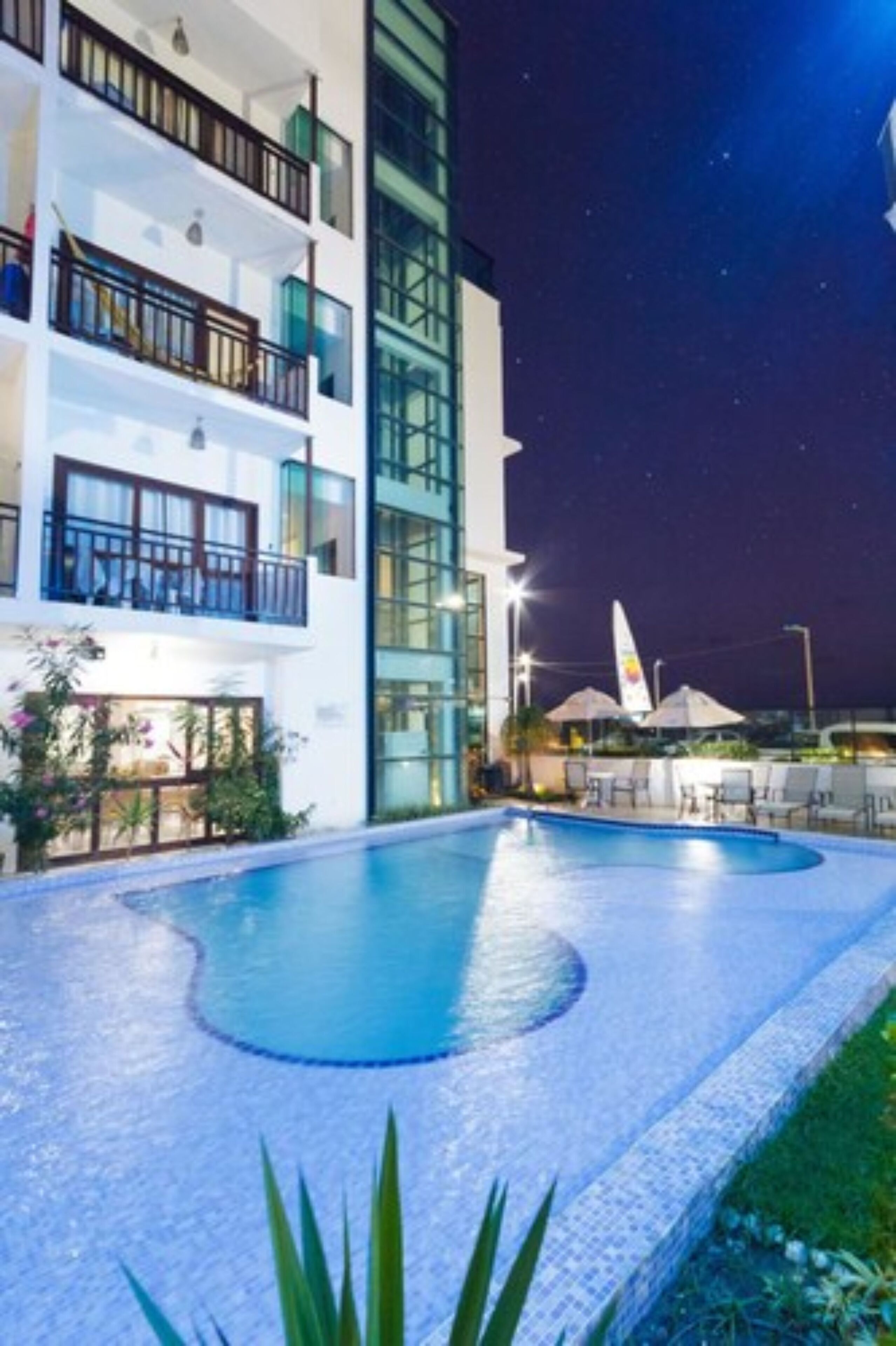 A modern hotel with a swimming pool, balconies, and a night sky view.