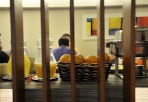 A kitchen area with a person preparing food, a basket of bread, and kitchen appliances. - Hotel El Vergel (Santiago)