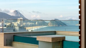Une vue depuis un balcon donnant sur une plage, avec une vue sur la ville en arrière-plan.