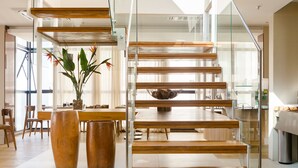 Un intérieur moderne avec un escalier en bois, un coin repas et une grande fenêtre.