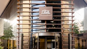 Un bâtiment moderne avec une façade en verre, un portail d’entrée en métal et une enseigne indiquant « Ritz Copacabana ».