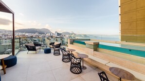 Une terrasse sur le toit avec des sièges extérieurs, une piscine et une vue sur la ville.
