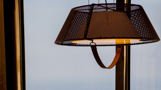 Une table dressée pour le dîner, avec vue sur l’océan grâce à de grandes fenêtres.