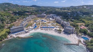 Luchtbeeld van een resort met meerdere gebouwen, een strand en een zwembad.