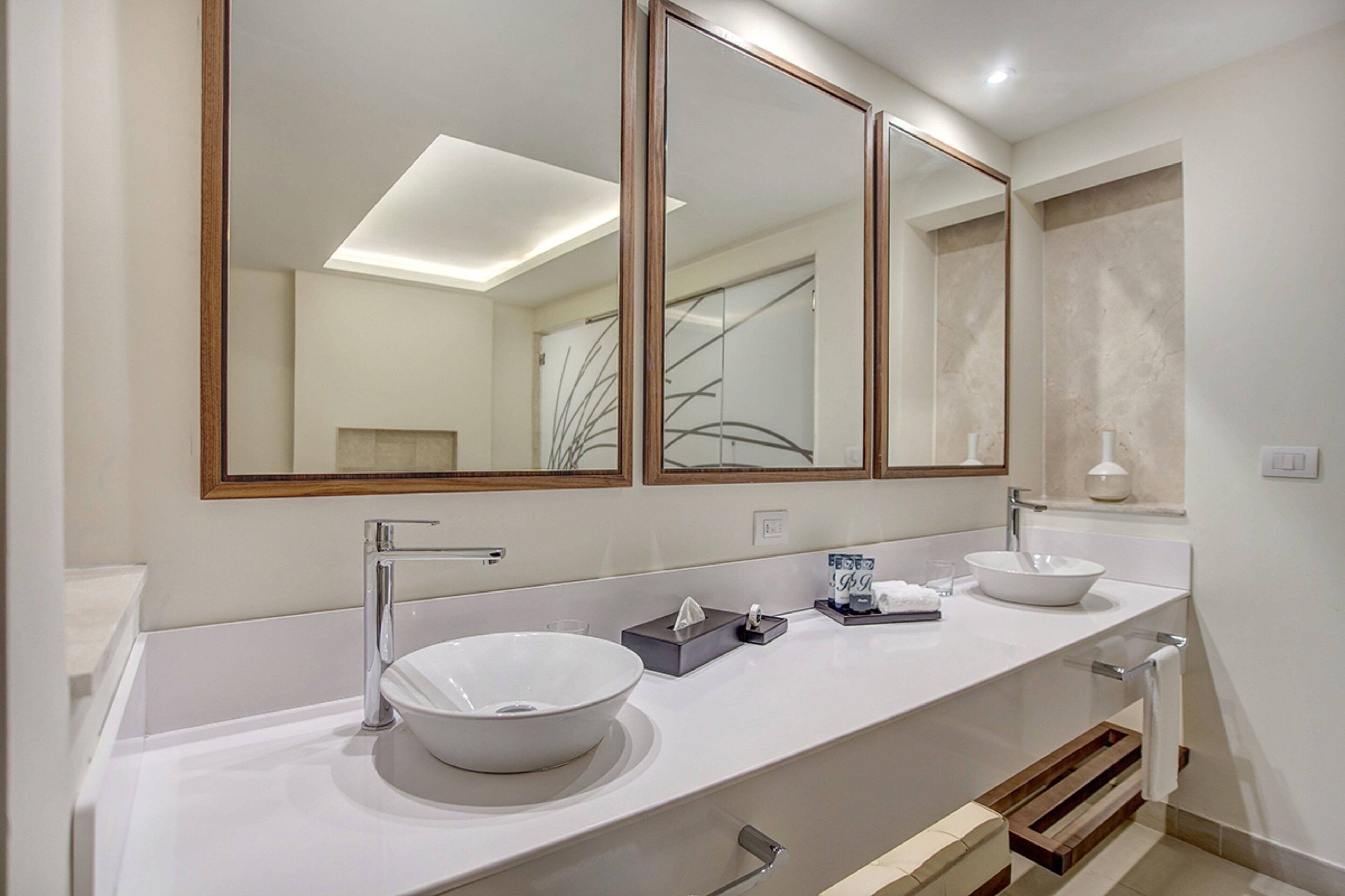 Un baño moderno con dos lavamanos, un espejo grande y un perchero para toallas.
