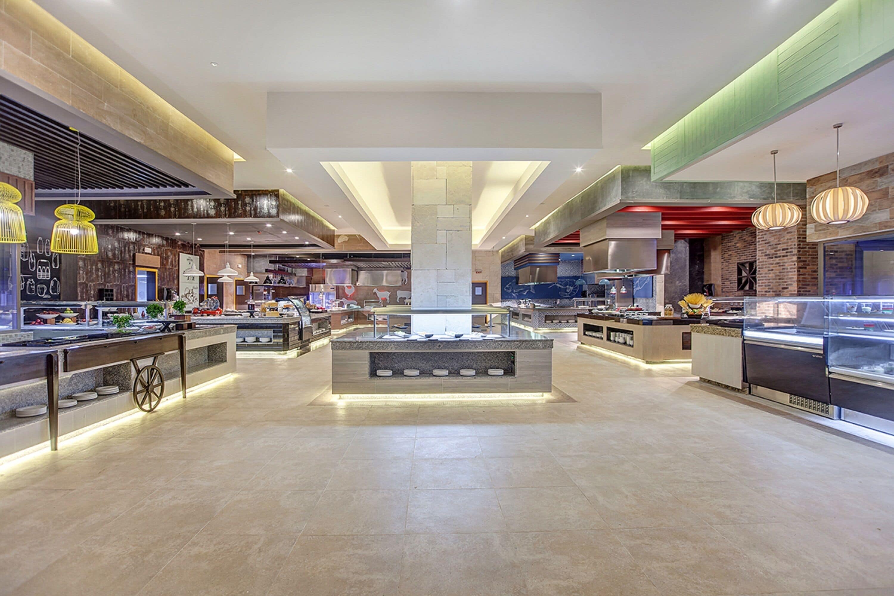 Un amplio vestíbulo de hotel con una isla central, varias zonas de estar y un diseño moderno.