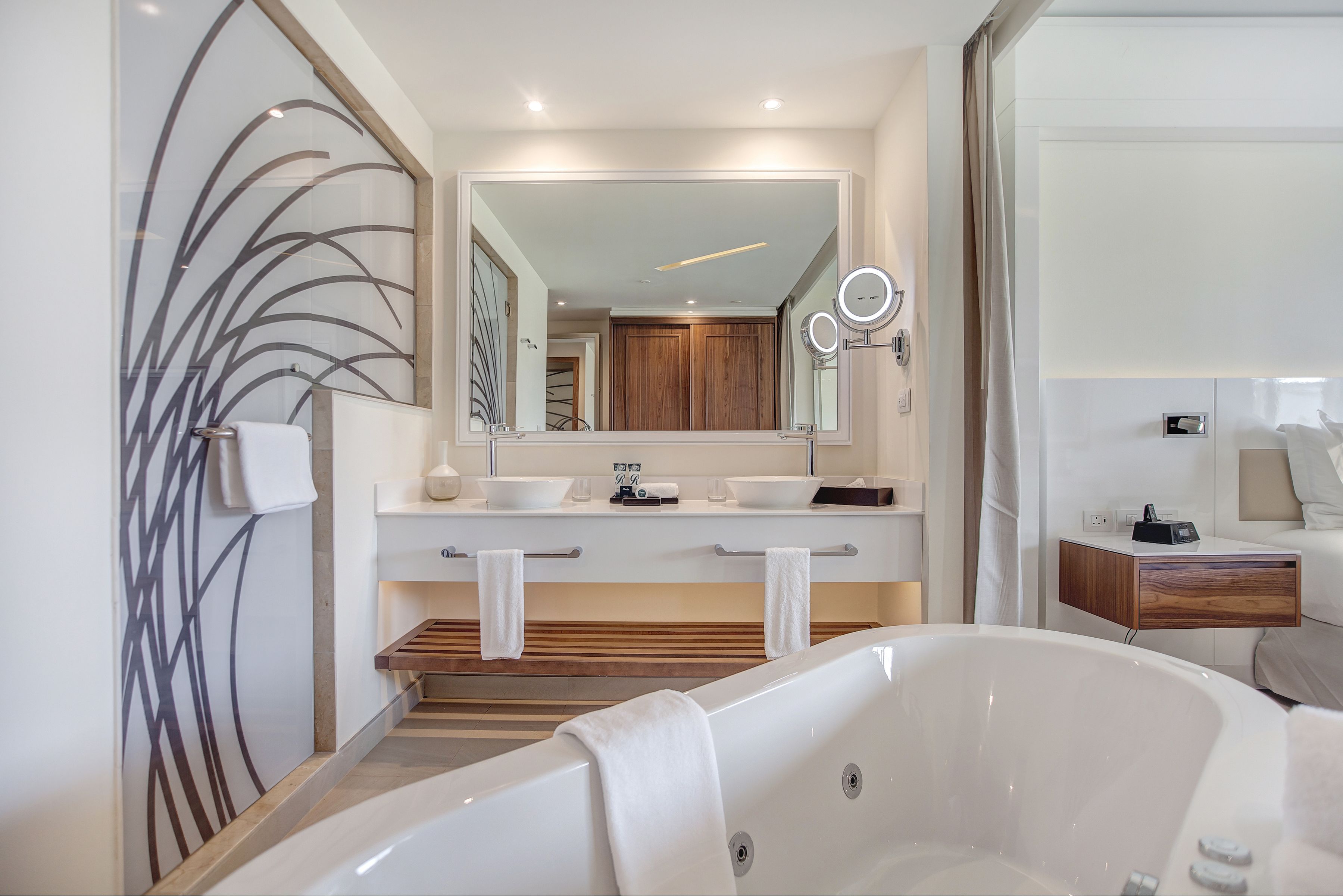 A modern bathroom with a freestanding bathtub, a large mirror, and a vanity with a wooden countertop.