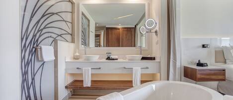 A modern bathroom with a freestanding bathtub, a large mirror, and a vanity with a wooden countertop.