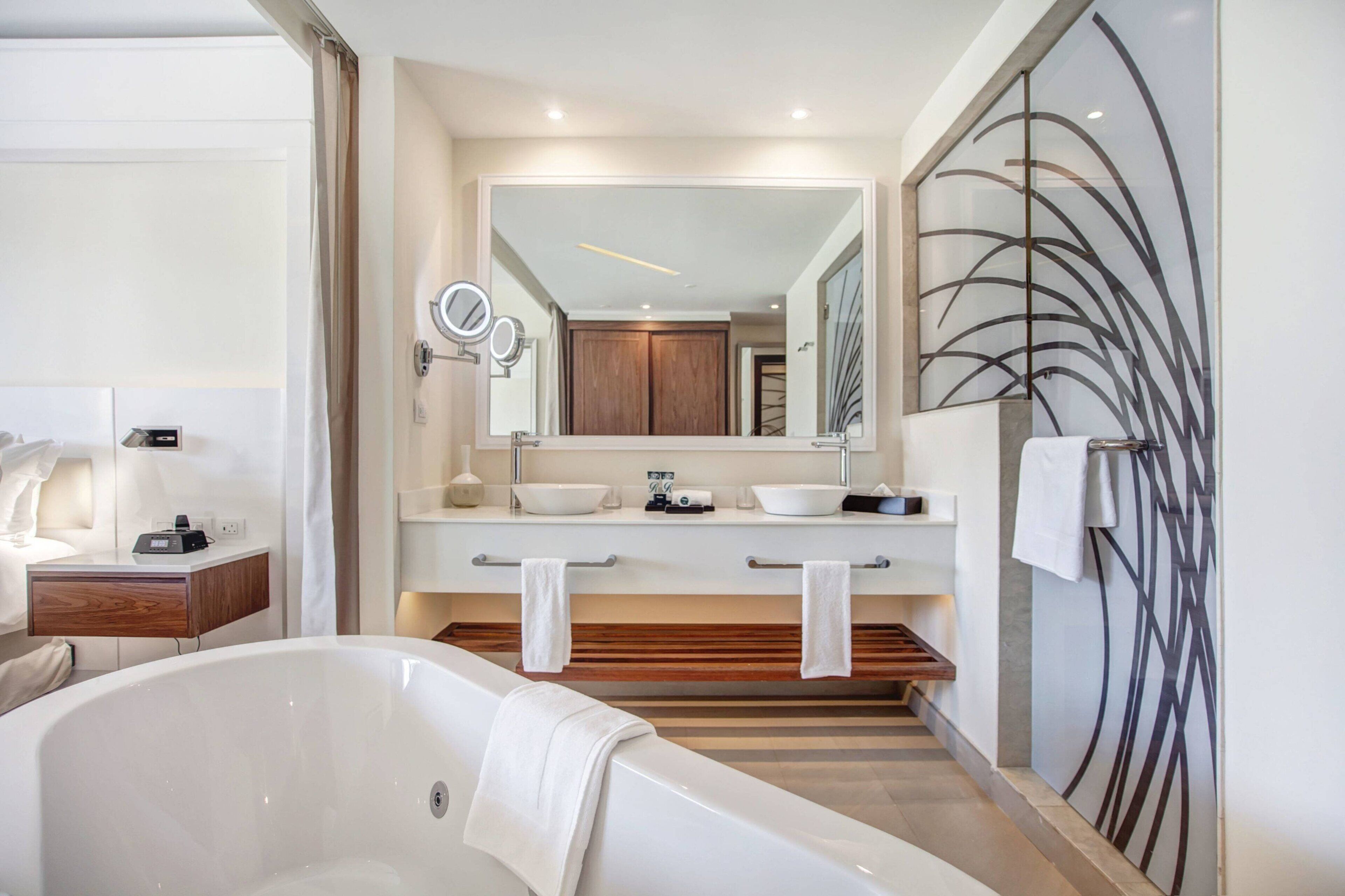 A modern bathroom with a freestanding bathtub, two sinks, and a large mirror above the vanity.