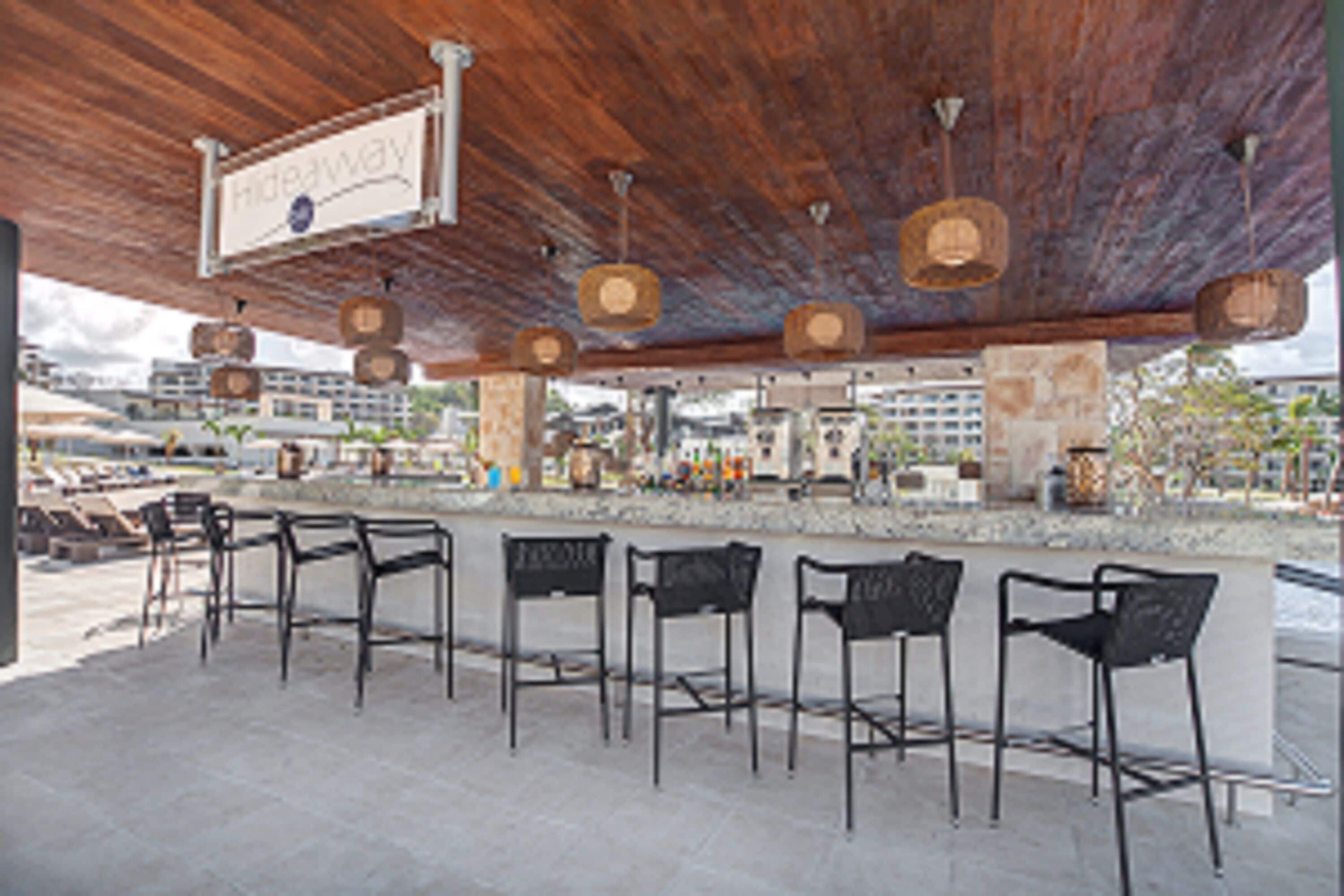 An outdoor bar area with wooden ceiling and hanging light fixtures.
