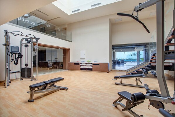 A gym with various exercise equipment, a bench, and a reception desk. - Royalton Hideaway Saint Lucia, An Autograph Collection All-Inclusive Resort - Adults Only (Gros Islet)