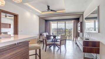 A modern kitchen with a central island, a dining area with a round table and chairs, and a large window with a view of the city.