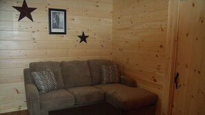 A cozy room with a wooden wall, a sofa, and a small table. - Shenandoah Valley Campground (Quicksburg)