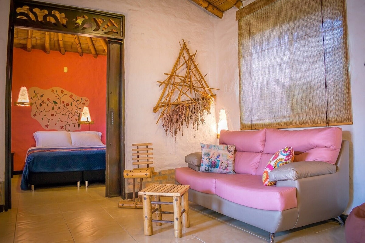 A cozy room with a bed, a pink sofa, and a small wooden stool.