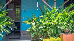 A blue building with a wooden porch, large green plants, and a small garden area. - Hotel Campestre Solar De La Luna (Armenia)