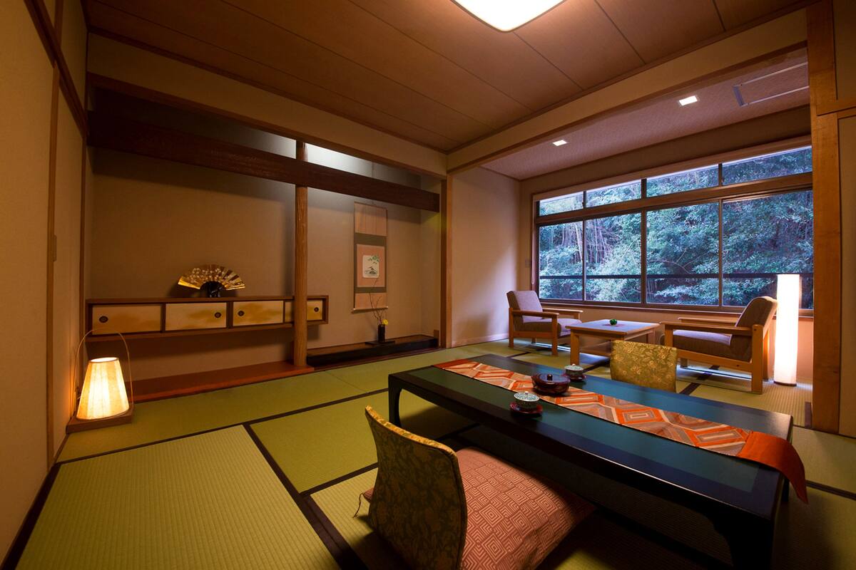 A traditional Japanese room with tatami flooring, a low table, and chairs.