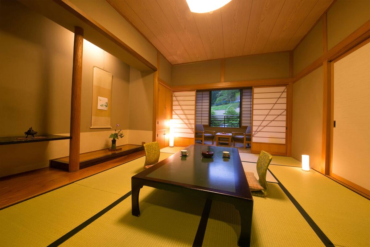 A traditional Japanese room with tatami flooring, a low table, and sliding doors.