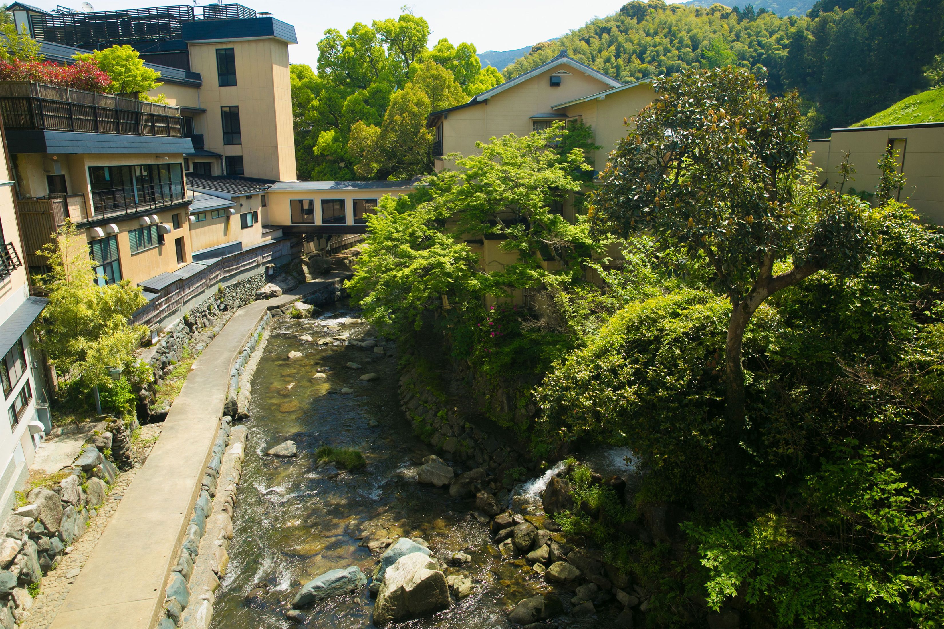 A residential area with a narrow stream, stone-lined pathway, and houses with balconies.