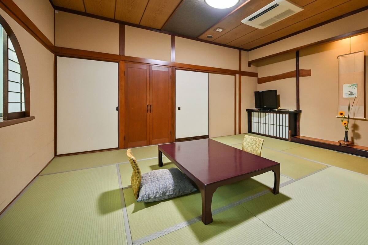 A tatami mat room with a low table, sliding doors, and a TV.