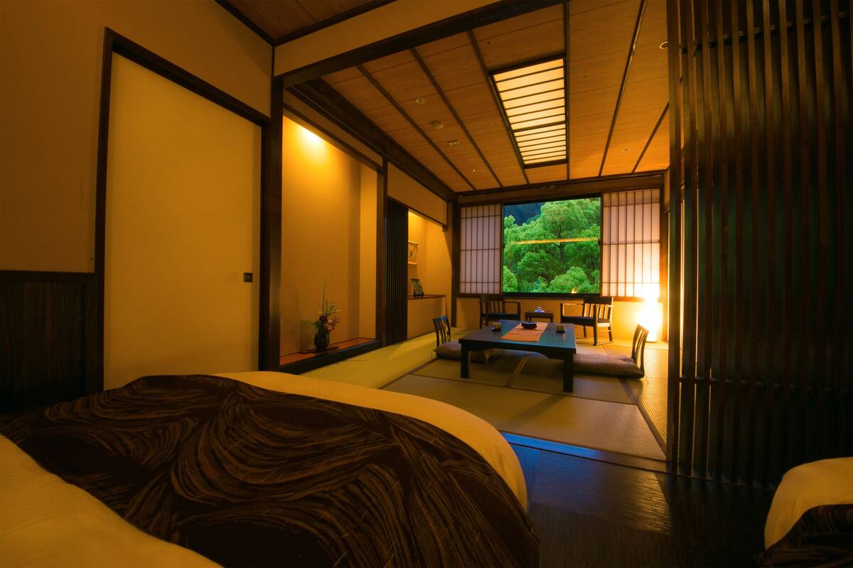 A traditional Japanese-style room with tatami flooring, a low table, and sliding doors leading to a garden.