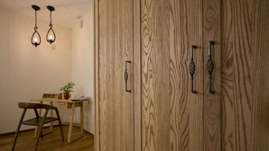 Une pièce comprenant une armoire en bois, un bureau avec une chaise et un luminaire suspendu.