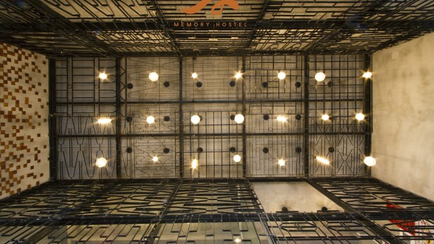 A modern interior with a geometric metal ceiling, a patterned wall, and a sign reading "MEMORY HOSTEL". - Memory Hostel (Da Nang)