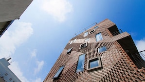 A multi-story building with a distinctive brick facade and multiple windows. - Memory Hostel (Da Nang)