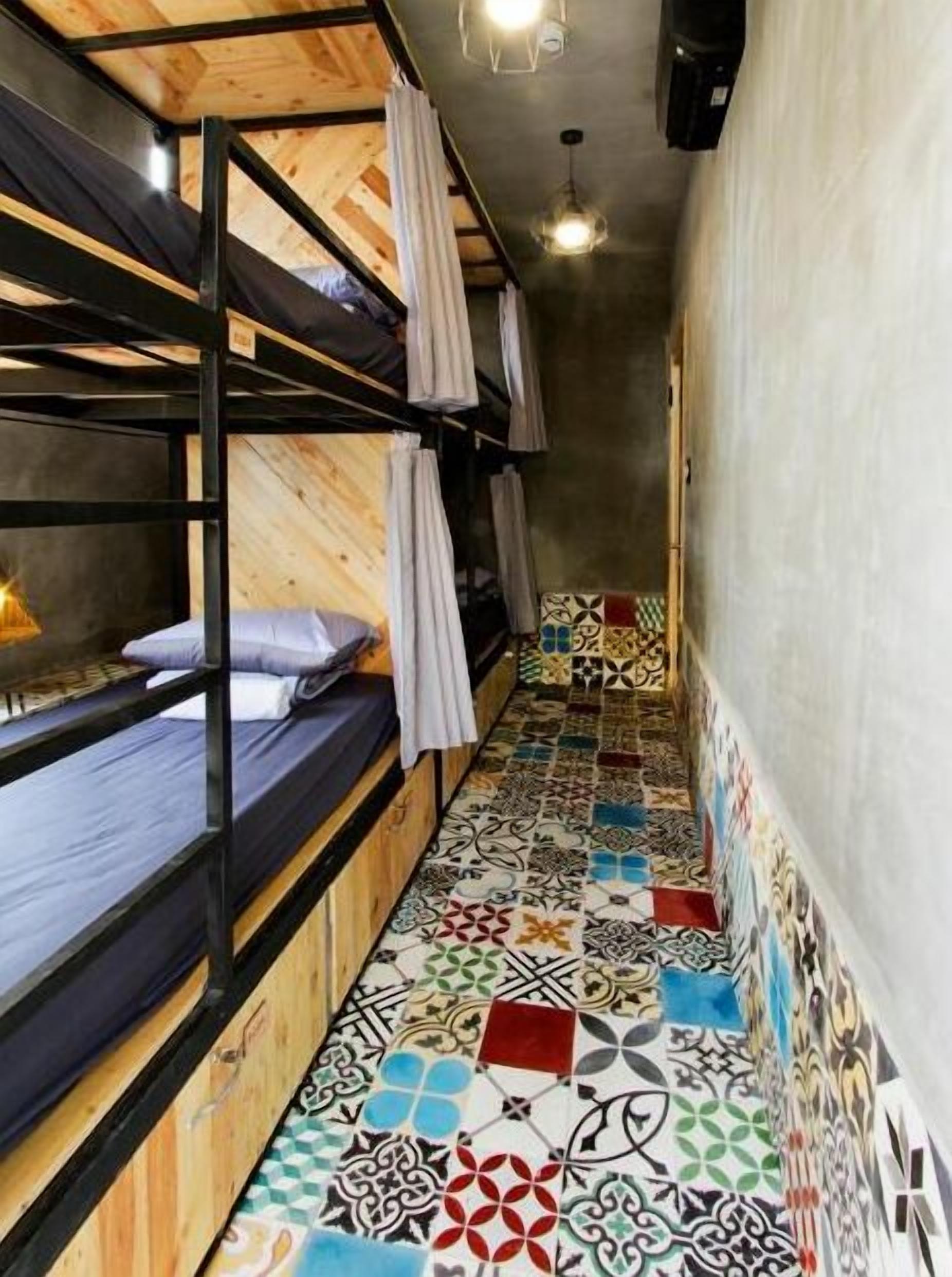 A narrow corridor with bunk beds on one side and a tiled floor.