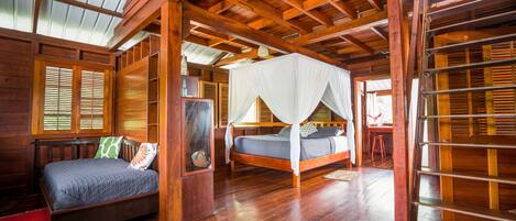 A wooden room with a bed, a smaller bed with a canopy, and a bookshelf.