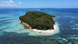 Vista aérea de una isla tropical con playa y aguas azul turquesa.