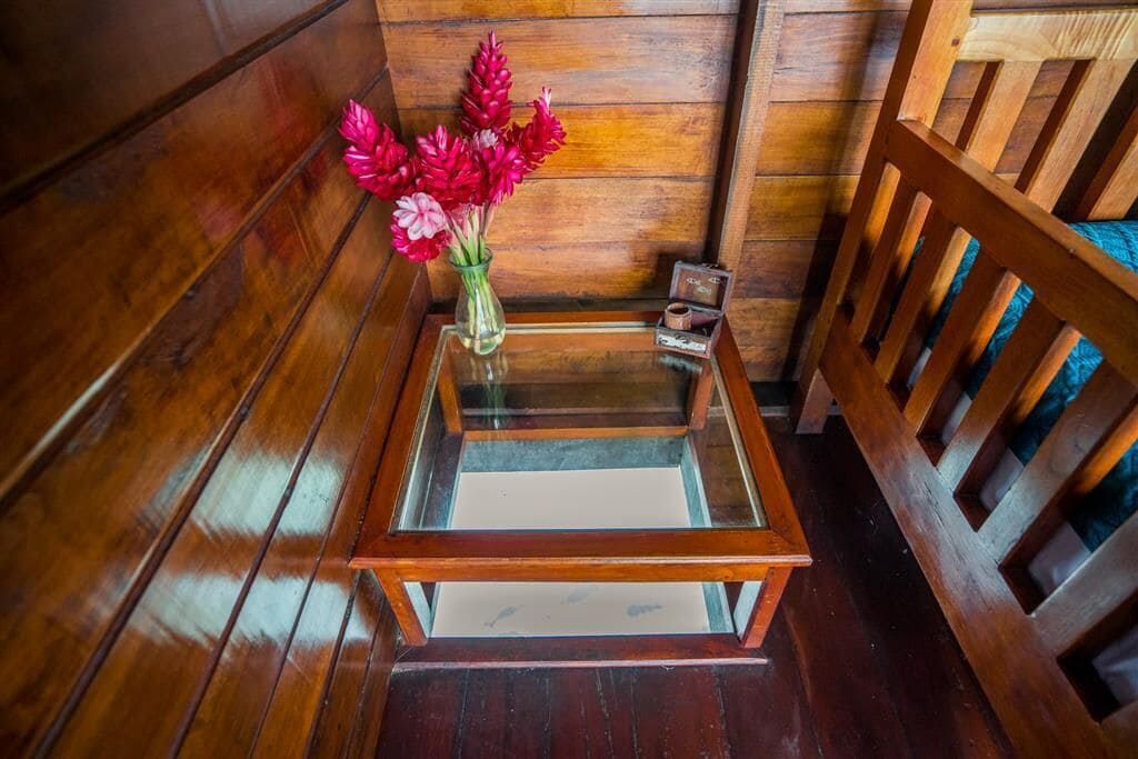 Un banc en bois, une table en verre et un vase rempli de fleurs rouges.