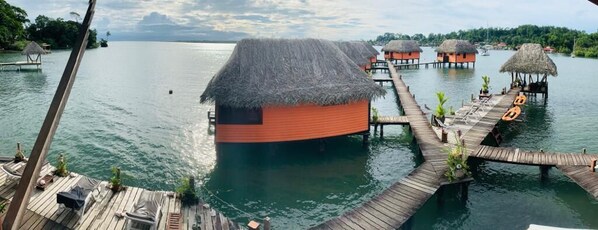 Cabañas sobre el agua conectadas por pasarelas de madera sobre aguas tranquilas.