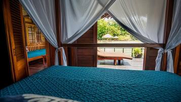 Un dormitorio con cama, cortinas y vista a un espacio exterior con banco y sombrillas.