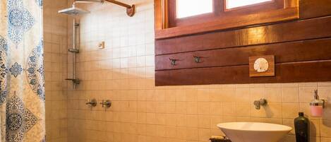 A bathroom with a shower, a sink, a clock, and a window.