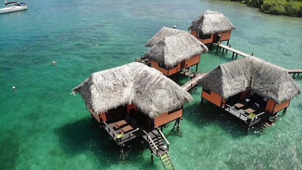 Bungalows sobre el agua con techos de paja y senderos de madera.