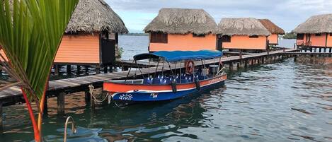 A boat docked at a pier with overwater bungalows in the background.