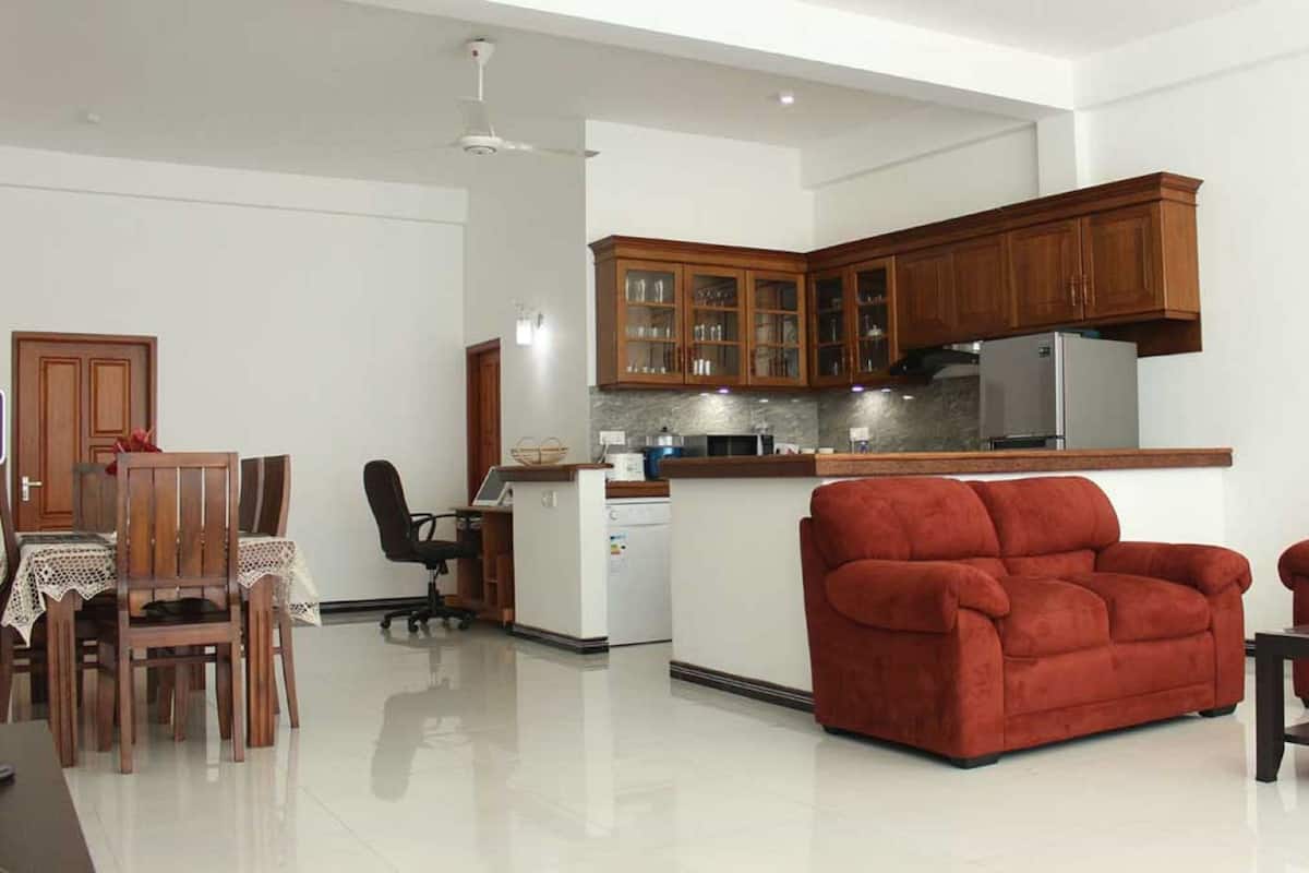 A spacious living room with a red sofa and a dining area with wooden furniture.