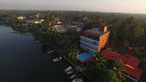 An aerial view of a coastal property with a swimming pool, multiple boats, and a large building with a red roof. - Ranga Holiday Resort (Aluthgama)