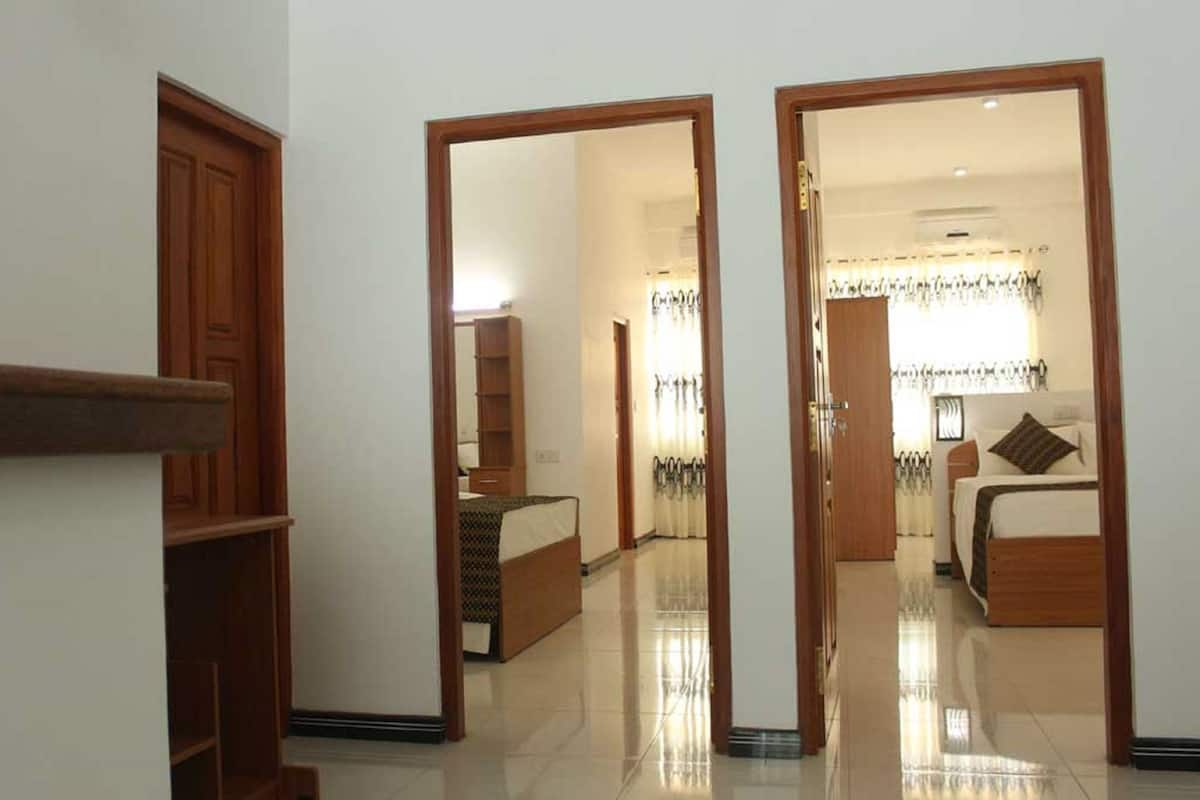 A hotel corridor with wooden doors, a bed, a wardrobe, and a mirror.