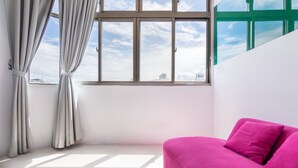 A room with a large window, a white wall, and a pink sofa. - Modena B&B (Taitung)