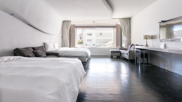 A modern hotel room with two beds, a desk, and a sofa. - Modena B&B (Taitung)