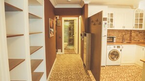 A hallway leading to a kitchen with a washing machine, a microwave, and cabinets. - My Suit Residence (Atakum)
