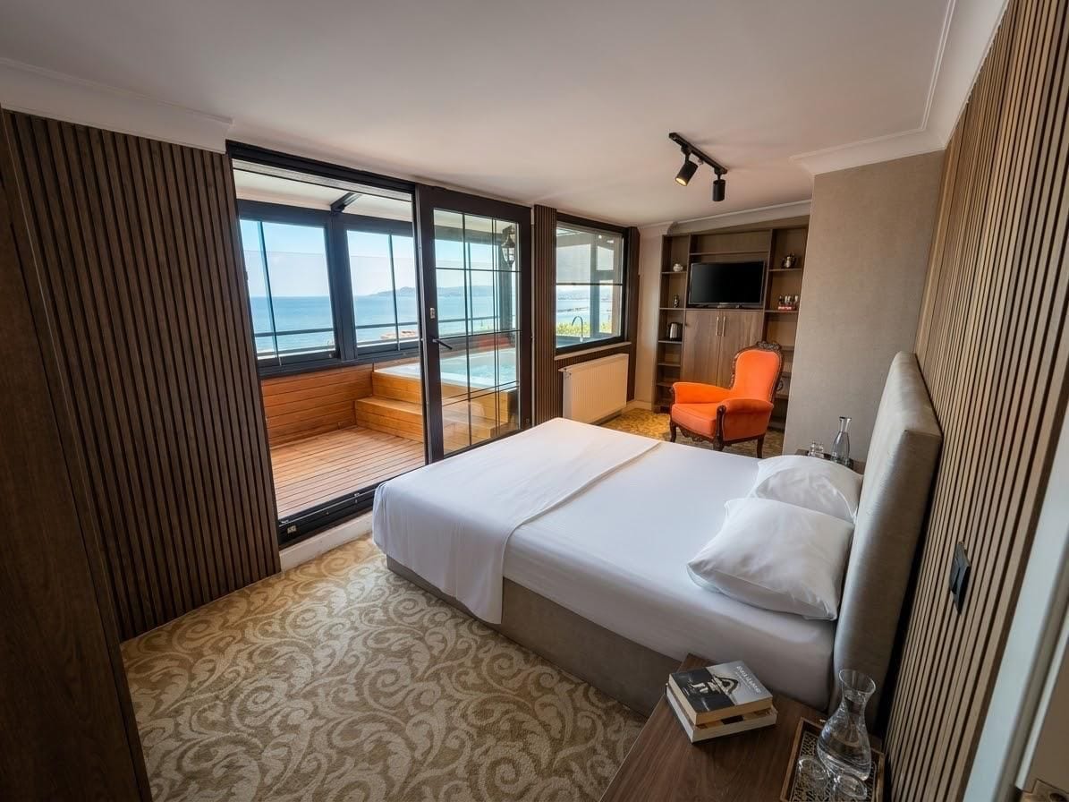A hotel room with a bed, a seating area with a view, a television, and a minibar.