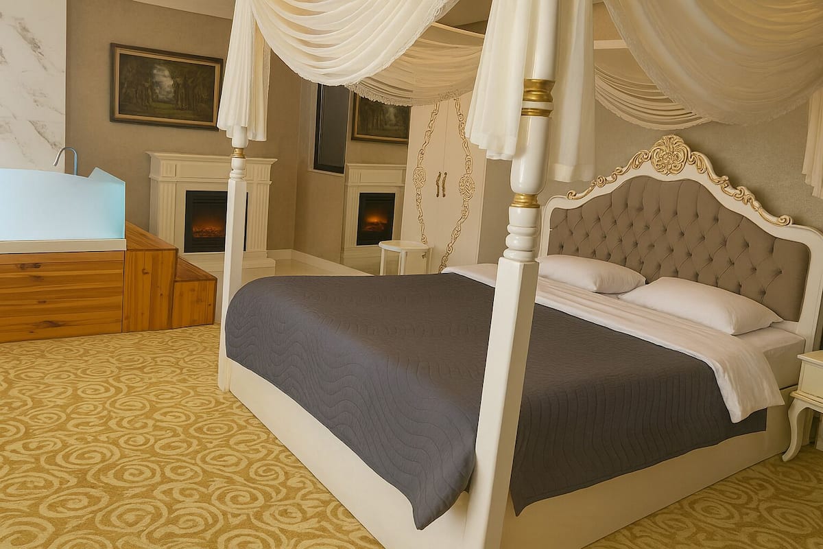 A four-poster canopy bed with a tufted headboard, a bedside table, and a nightstand.
