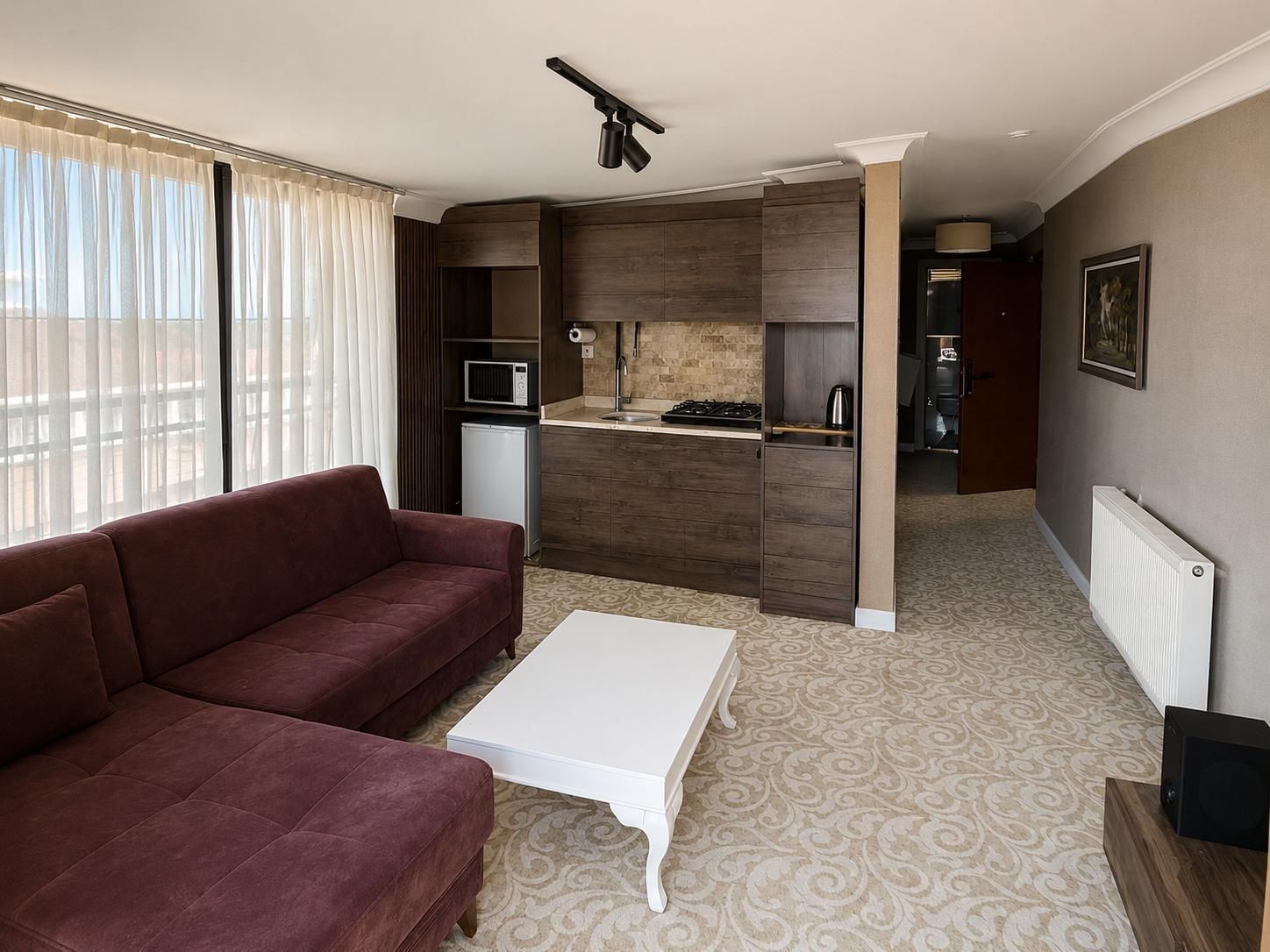 A compact living space with a sofa, a coffee table, a kitchenette, and a radiator.