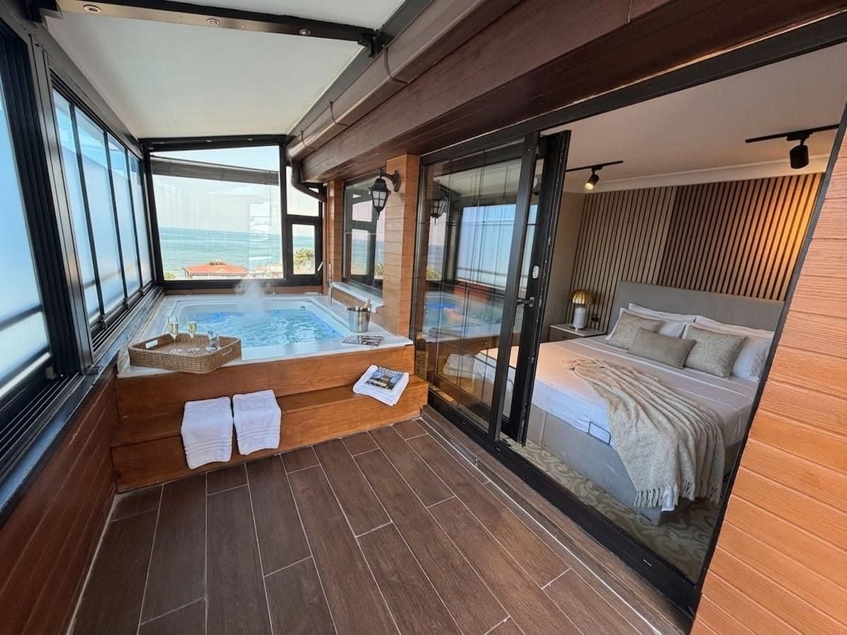 Ein Balkon mit Whirlpool, einem Bett und Meerblick.