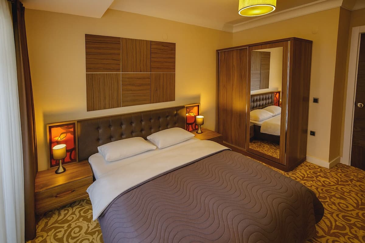 A hotel room with a large bed, a wardrobe, and a mirror.