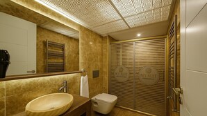 A modern bathroom with a large mirror, a wooden vanity, a sink, a toilet, and a shower with a sliding door. - My Suit Residence (Atakum)